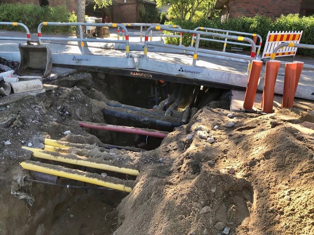 Katutyömaa, jossa kaivanto ja näkyvillä olevia putkia, suojakaiteet ja varoitusmerkit.