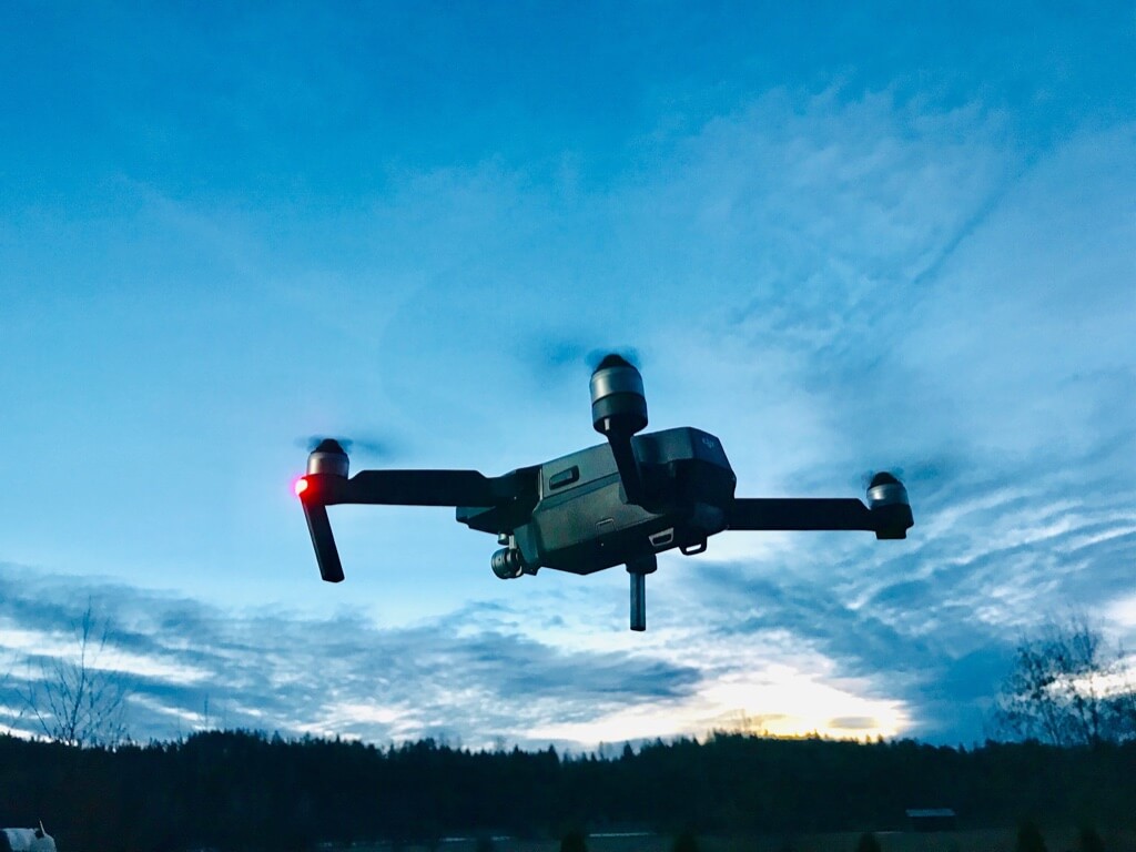 Lentävä nelimoottorinen drone sinitaivaalla auringonlaskun aikaan.