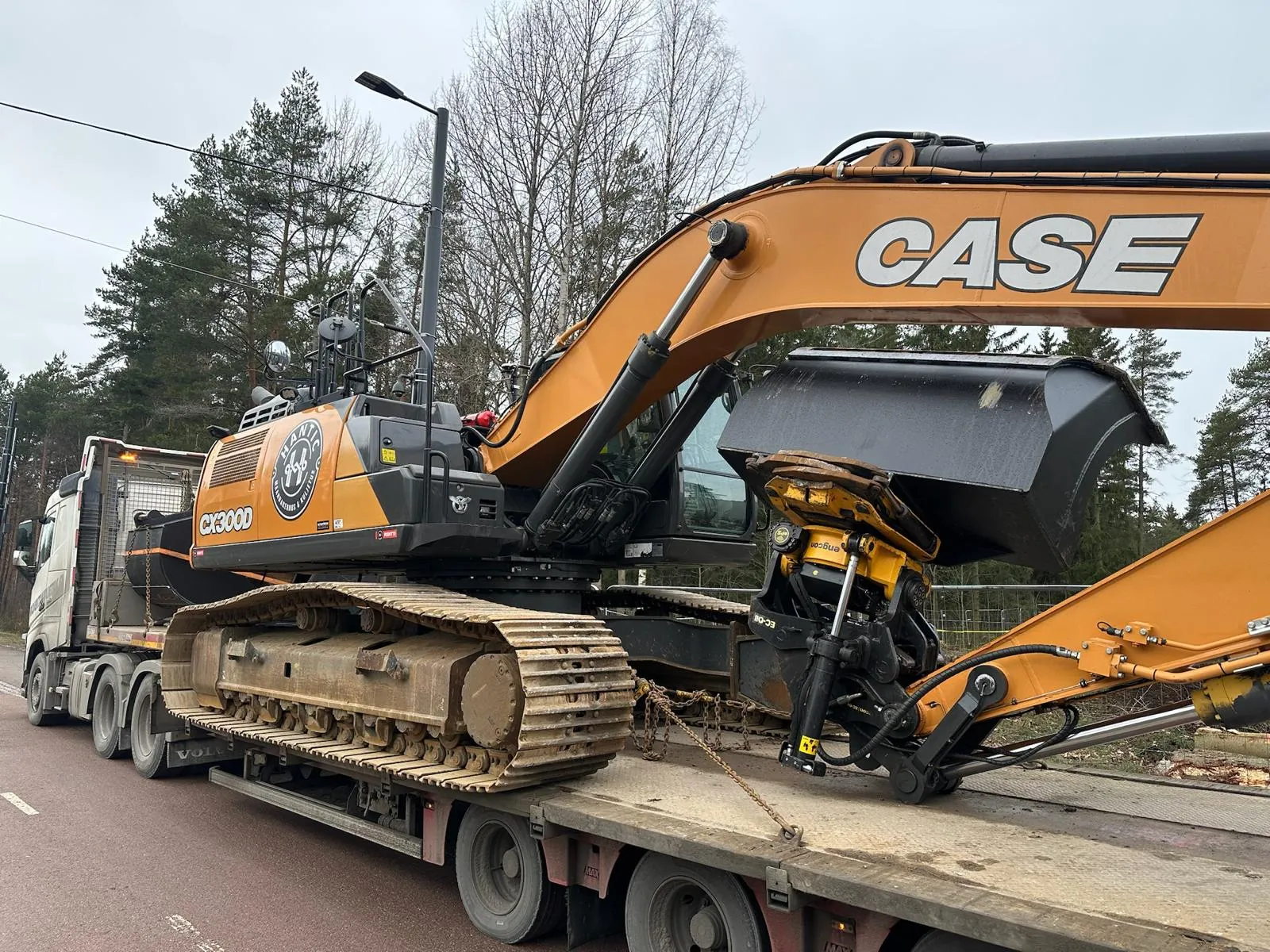 Kaivinkone kiinnitettynä rekka-auton lavalle puistotien vieressä metsässä.